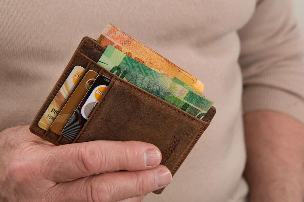Hand holding an open wallet with cash, illustrating common money mistakes