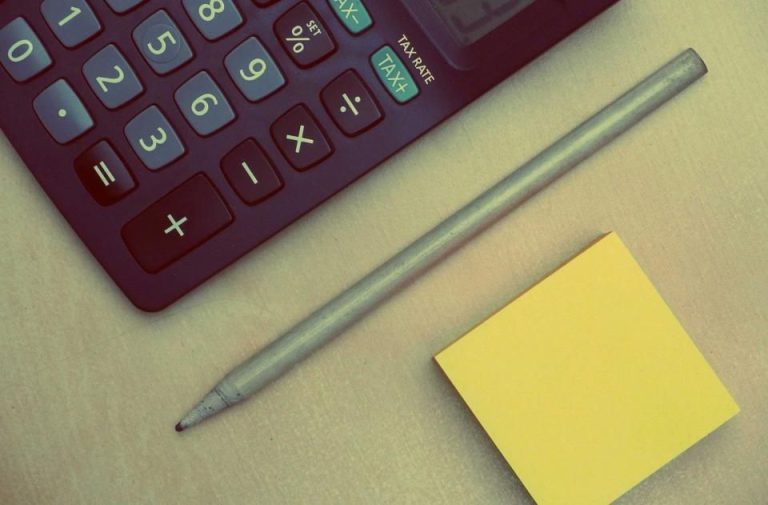 Calculator, pencil and sticky note on a desk for learning how to make a budget