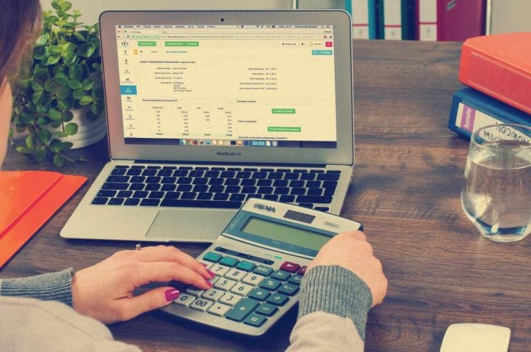 Person using a calculator next to a laptop with financial charts, illustrating what is personal finance