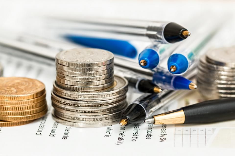 Stacks of coins beside pens and financial paperwork, showing why personal finance is important